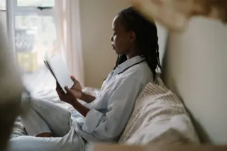 women reading a paper book in bed