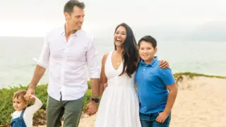 Family of 4 holding hands walking on the beach