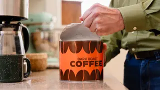 Man opening a paper can of coffee beans.