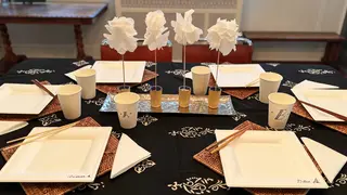 A dinning table set with paper plates, napkins and cups