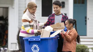 Parent and kids recycling outside the house